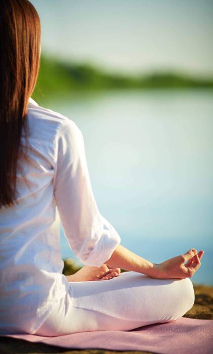 Half back of meditating woman relaxing in pose of lotus outdoors